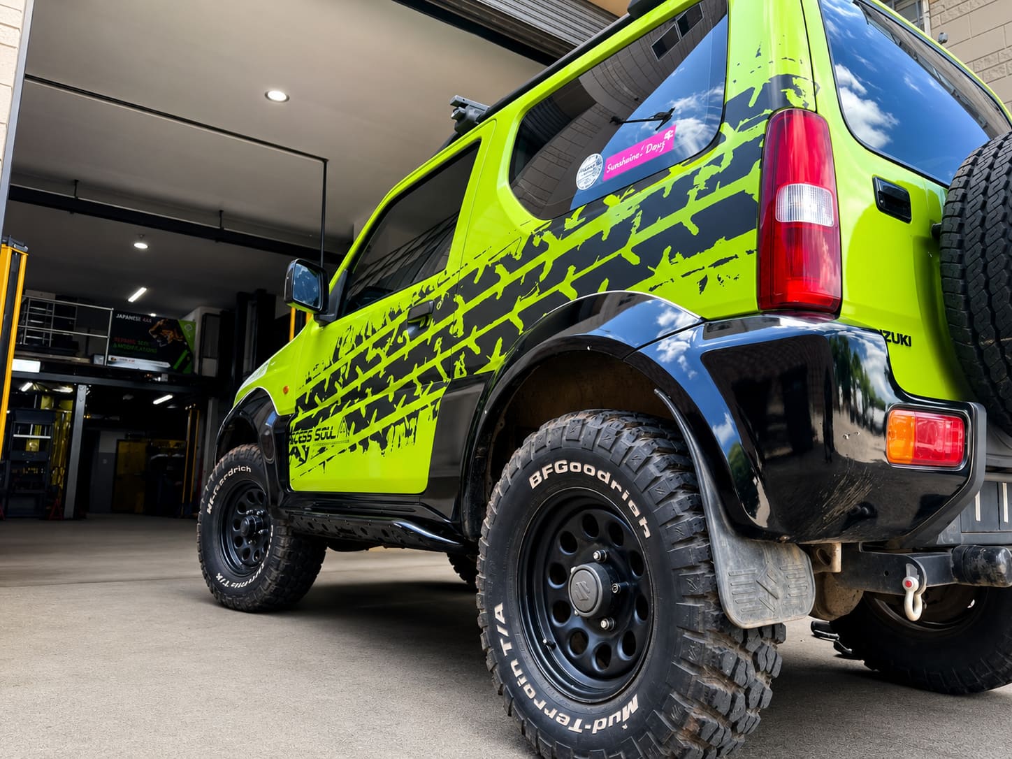 Green Suzuki Jimny rear quarter with tyre-tread vehicle wrap